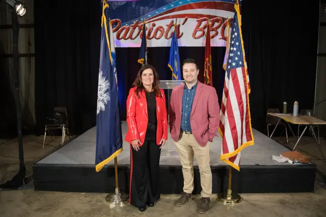 Two guests pose between the South Carolina and United States flags