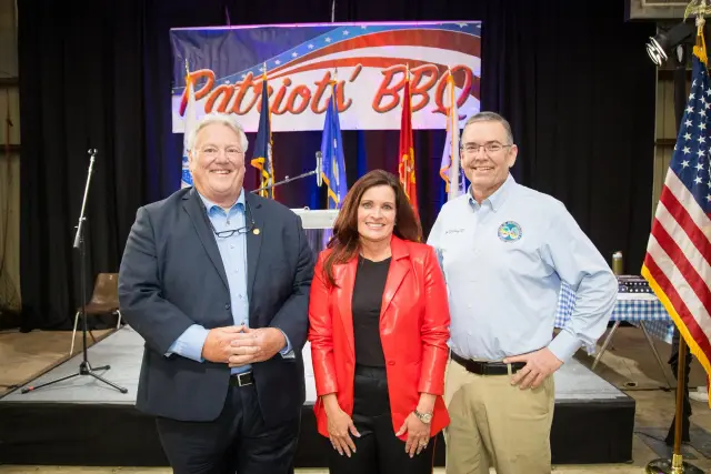 Three guests pose in front of the stage