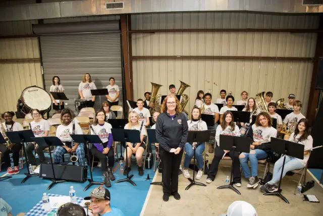 A school band seated with their instruments and their director
