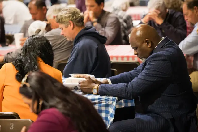Guests bow their heads at their tables